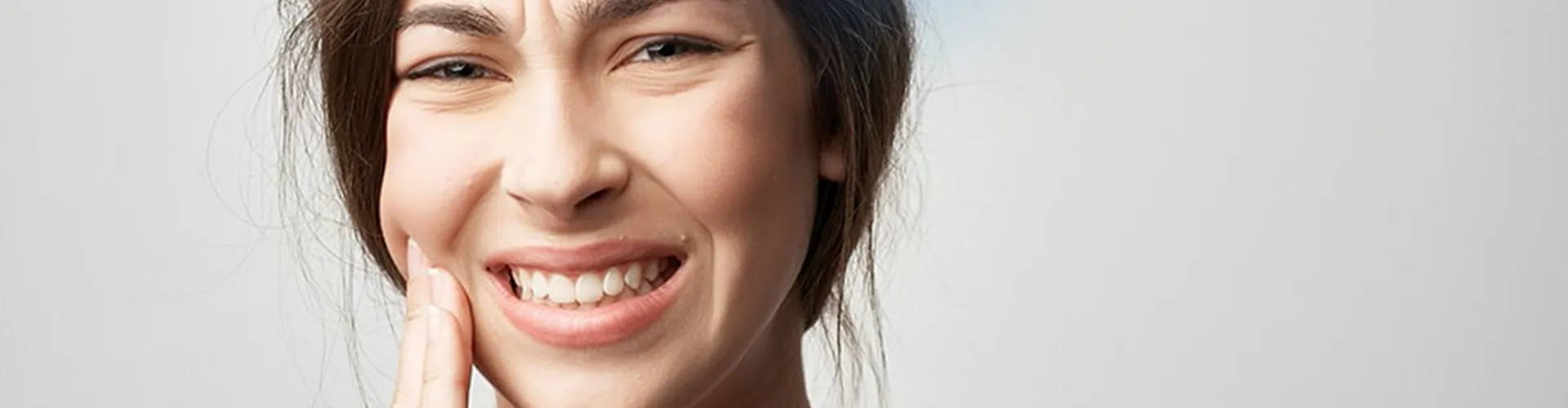 Woman holding cheek in pain.