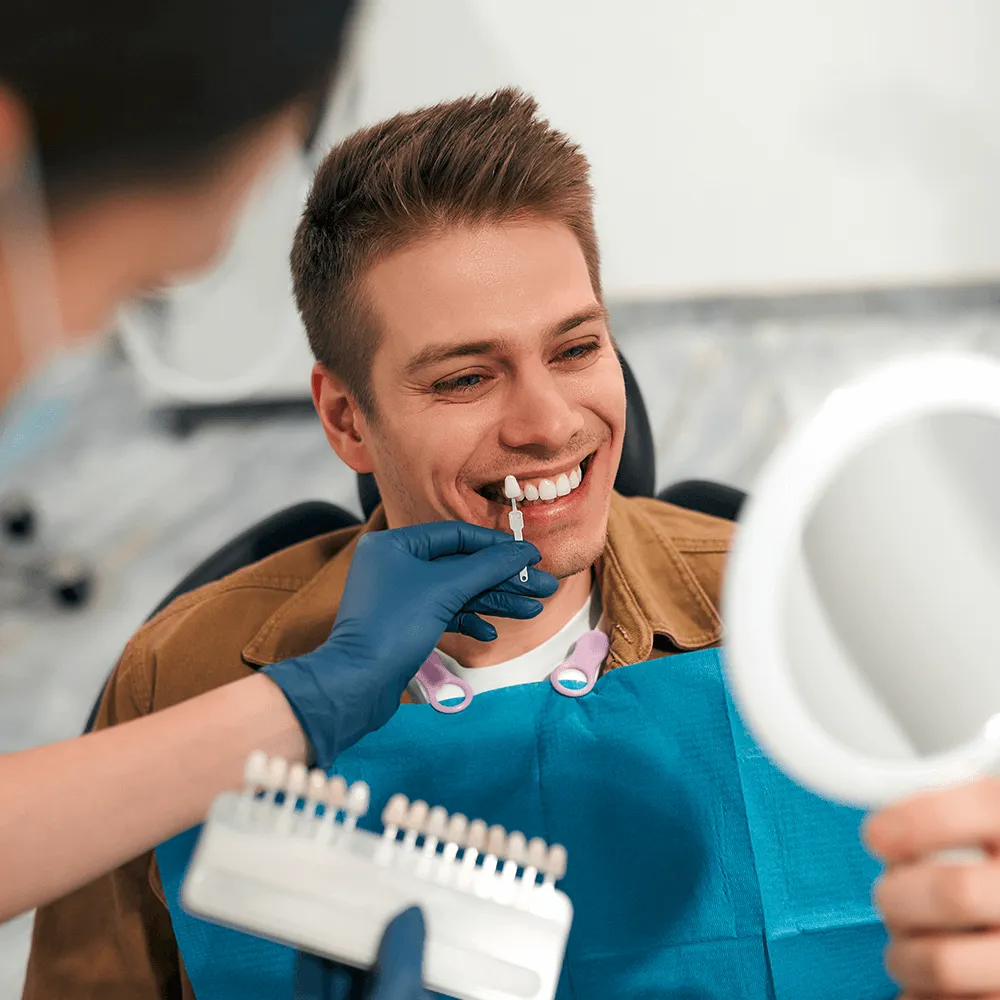 Dentist looking in mirror with veneers held by dentist.