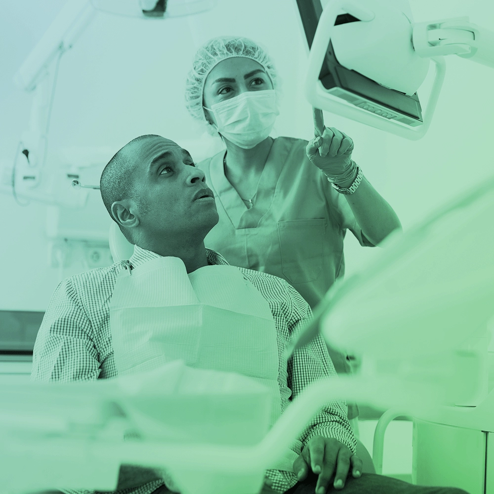 Dentist showing something to patient on screen.