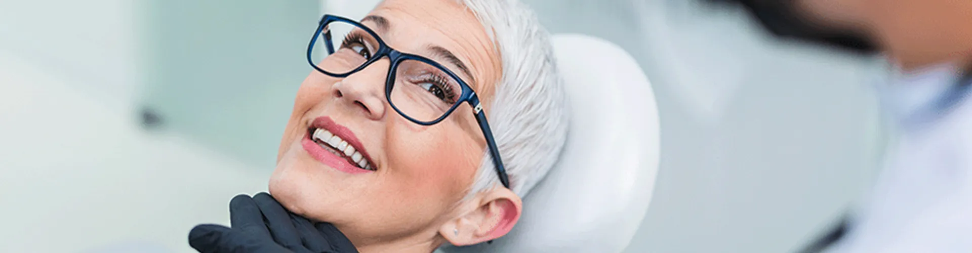Gloved hand lifting the chin of smiling woman.