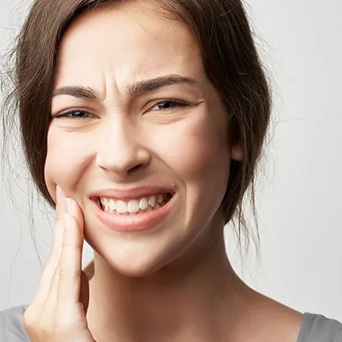 Woman holding cheek in pain.